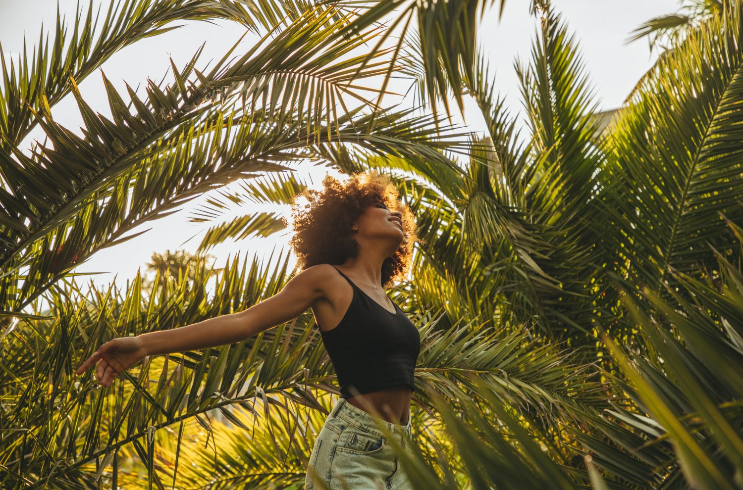 Pretty young afro woman among palm trees